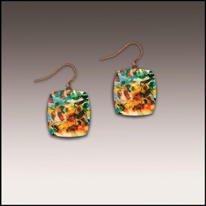 May include: A pair of square earrings with a colorful leaf design. The earrings have copper-colored hooks and feature a vibrant mix of orange, yellow, green, and blue hues, creating a nature-inspired aesthetic. The earrings are a unique accessory.