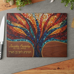 May include: Rectangular cutting board featuring a mosaic tree design in red, orange, blue, and yellow. The tree is set against a dark wood grain background. The text "Jacobs family" and a date are displayed in gold lettering.