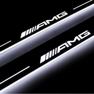Puede incluir: Dos umbrales de puerta de coche iluminados con el texto blanco "AMG" y un diseño estilizado. Los umbrales están sobre un fondo negro, con líneas blancas. Accesorio automotriz.