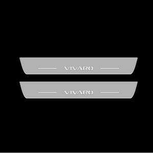 May include: Two silver-grey car door sill protectors with the word "VIVARO" in a white, sans-serif font. Each protector has a horizontal line above and below the text. The background is black.