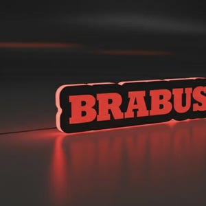 Può includere: Un'insegna rossa "BRABUS" con un bordo nero, illuminata su uno sfondo scuro. Il bagliore dell'insegna si riflette sulla superficie sottostante. Il design è moderno ed elegante.