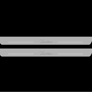 May include: Two silver-colored car door sills with the Cadillac logo in a stylized font. Each sill has a thin, horizontal line and a curved edge. The background is solid black.