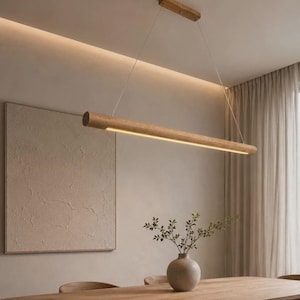 May include: A linear pendant light fixture featuring a long, cylindrical wooden beam with an integrated LED light strip running along the bottom. The fixture is suspended from the ceiling by two thin wires attached to a rectangular wooden mount.
