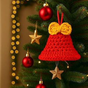 May include: A red crocheted bell Christmas ornament with a yellow bow at the top, hanging on a green Christmas tree. Other decorations include red baubles and gold star ornaments. The background features blurred, warm, golden lights.