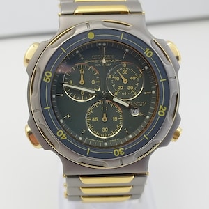 Op de afbeelding: Een witte keramische mok met een zwart handvat en de tekst "But First, Coffee" in een zwarte, vette letter. De mok staat op een wit oppervlak.