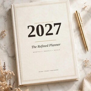 Peut inclure: Un agenda couleur crème avec une bordure dorée et le texte 2027, XMFDZ COLLECTION, The Refined Planner, MONTHLY, WEEKLY, GOALS, et US Letter, Printable, instant download. Un stylo doré est posé à côté de l'agenda sur un marbre blanc.