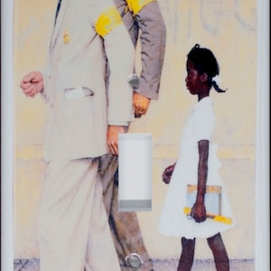 Op de afbeelding: Een lichtschakelaar-afdekplaat met een schilderij van een jong meisje in een witte jurk dat naar school loopt, begeleid door twee mannen in pak. Het schilderij is getiteld "The Problem We All Live With" door Norman Rockwell.