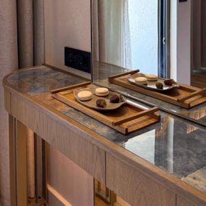 May include: A wooden vanity with a marble top and a large mirror. Two wooden trays hold macarons and chocolate-covered strawberries. The vanity is in a well-lit room with a neutral color palette.