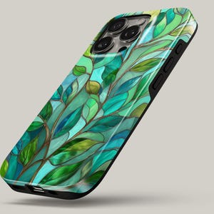 May include: A smartphone case featuring a stained-glass design with green and blue leaf patterns. The case has a black border and a glossy finish, creating a vibrant and artistic look. The design resembles a botanical theme.