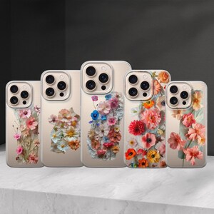 Puede incluir: Una colección de cinco fundas para teléfono con diseños florales. Cada funda presenta una disposición diferente de flores coloridas, incluyendo flores rosas, naranjas, amarillas y azules, sobre un fondo neutro. Las fundas están diseñadas para varios modelos de teléfono.