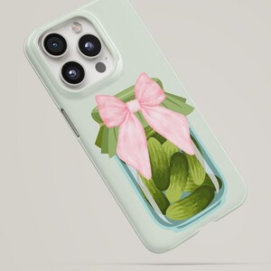 Op de afbeelding: Lichtgroene telefoonhoes met een aquarel illustratie van een pot augurken. De pot is versierd met een roze strik en groene bladeren. De hoes heeft een glanzende afwerking en een camera-uitsparing.