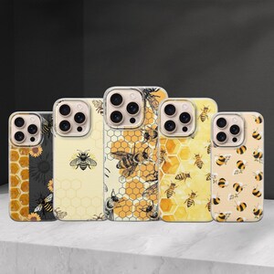 May include: A selection of phone cases with bee-themed designs. The cases showcase patterns such as honeycombs, bees, and sunflowers, in yellow, black, and cream hues. The cases are presented on a white surface against a dark backdrop.