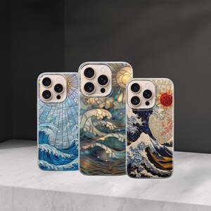 May include: Three phone cases with ocean wave designs. The cases feature a stained glass style with blue, white, and gold colors. Each case has a different sun and wave pattern. The cases are displayed on a white surface.