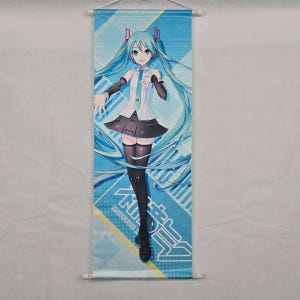May include: A wall scroll featuring a full-body illustration of a female anime character with long, turquoise hair. She wears a white top, black skirt, and black thigh-high stockings. The background is blue with geometric designs and Japanese text.