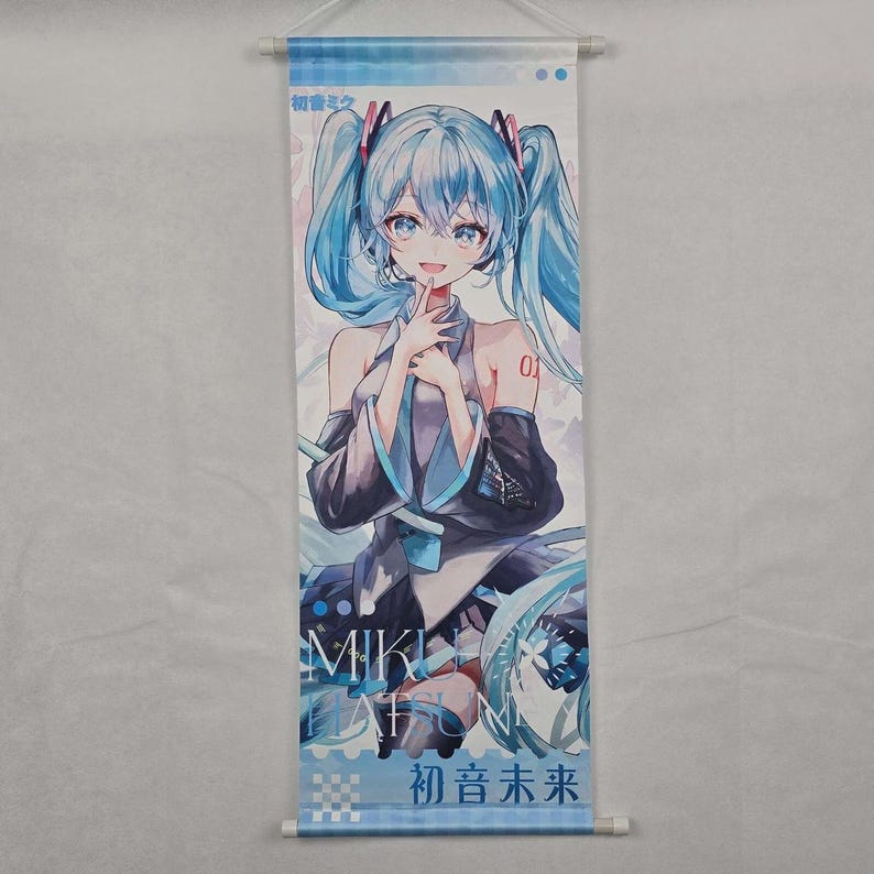 May include: A vertical wall scroll featuring a blue-haired anime character with a finger to her lips. The character wears a black and blue outfit. The scroll has Japanese text and the name "Miku Hatsune".