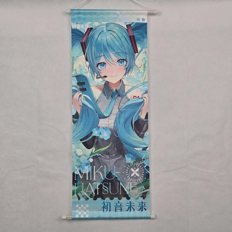 May include: A wall scroll featuring a blue-haired anime character with a microphone headset. The character is wearing a gray and black outfit with a blue tie. The scroll has the text "MIKU HATSUNE" and Japanese characters.
