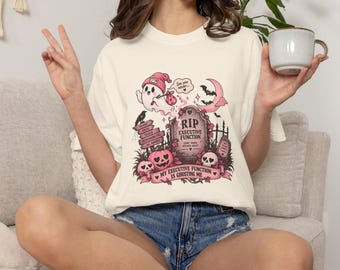 May include: An off-white t-shirt featuring a pink and black graphic of a ghost, a tombstone labeled RIP EXECUTIVE FUNCTION, pumpkins, and skulls. The text reads: See you never, PLANS, IDEAS, TASKS, RESPONSIBILITIES, ALL IGNORED, and MY EXECUTIVE FUNCTION IS GHOSTING ME.