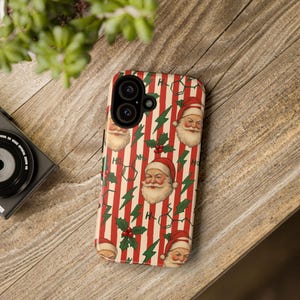 Op de afbeelding: Een telefoonhoesje met een feestelijk kerstontwerp. De hoes heeft een herhalend patroon van kerstmannen, rood-witte strepen, groene bliksemschichten, hulst en chemische structuren. De hoes ligt op een houten oppervlak.