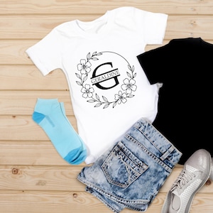Puede incluir: Una camiseta blanca con un dise&ntilde;o de corona floral y el nombre "Geraldine" impreso. La imagen tambi&eacute;n incluye unos shorts vaqueros, una camiseta negra, calcetines azul claro y zapatillas plateadas.