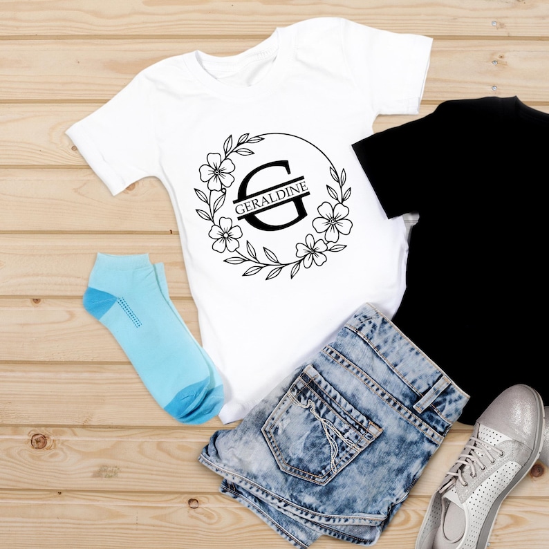 Puede incluir: Una camiseta blanca con un dise&ntilde;o de corona floral y el nombre "Geraldine" impreso. La imagen tambi&eacute;n incluye unos shorts vaqueros, una camiseta negra, calcetines azul claro y zapatillas plateadas.