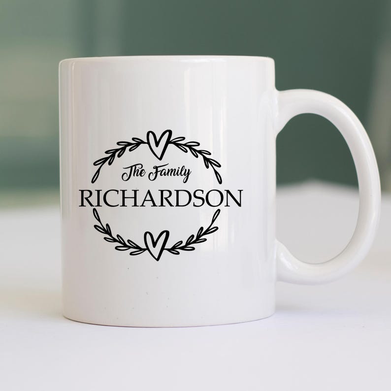 Puede incluir: Taza de cer&aacute;mica blanca con un dise&ntilde;o negro. El dise&ntilde;o incluye las palabras "The Family RICHARDSON" dentro de una corona con dos corazones. La taza tiene un asa curva y es adecuada para bebidas fr&iacute;as o calientes.