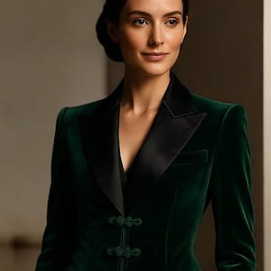 Puede incluir: Una blazer de terciopelo verde oscuro con solapa de satén negro y tres cierres de rana decorativos. La chaqueta entallada tiene un diseño clásico con cuello con muescas y dos bolsillos delanteros. Una prenda de abrigo sofisticada.