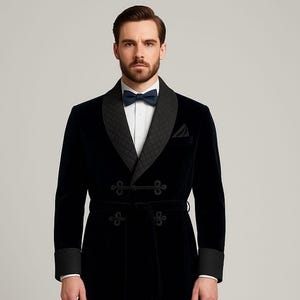 Puede incluir: Una bata de terciopelo negro con cuello chal acolchado y puños. La bata presenta un cierre cruzado con botones decorativos y un cinturón a juego. Se ve una pajarita azul marino.