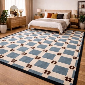 May include: A rectangular rug with a geometric pattern in a bedroom. The rug has a light blue and cream square design with dark brown accents and a black border. The rug is on a wooden floor. The room includes a bed and wooden furniture.