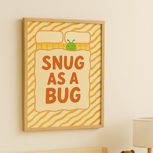Peut inclure: Une affiche encadrée avec le texte "SNUG AS A BUG" au-dessus d'un lit avec une literie blanche et un oreiller orange. Un petit ours en peluche marron est posé sur une table de chevet en bois à côté d'une lampe.