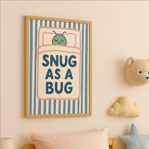 May include: A framed print with a light wood frame. The artwork shows a cartoon bug in bed with the text "SNUG AS A BUG" in blue letters. The background has blue and white vertical stripes. Decorative items are on the wall.