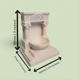 May include: A beige, speckled, stone-like fountain structure featuring two columns, a central basin, and an arched top. The dimensions are 127mm (5 inches) in height, 87mm (3.4 inches) in depth, and 101mm (3.9 inches) in width.