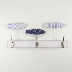 May include: White wooden coat rack with three hooks shaped like fish. The fish are painted in shades of blue and white.