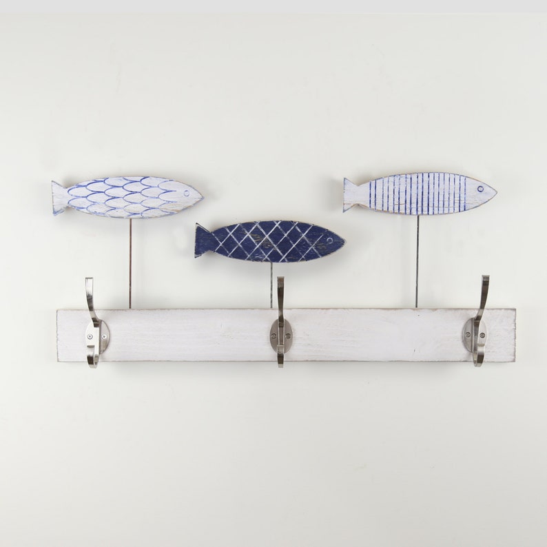 May include: White wooden coat rack with three hooks shaped like fish. The fish are painted in shades of blue and white.