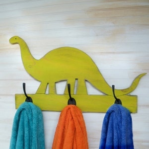 By Haven America- Key Lime Pie Green Painted wooden dinosaur shaped towel rack with three black metal hooks.