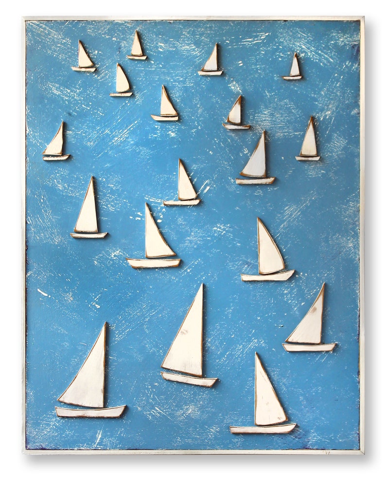 May include: A blue wooden wall art piece with white sailboats of various sizes arranged in a scattered pattern. The sailboats are raised from the surface, giving the piece a 3D effect.
