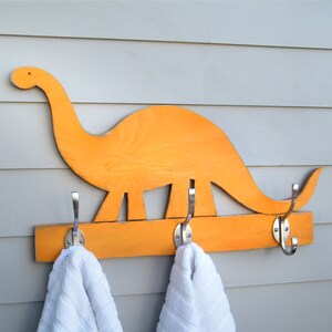 Our Florida Orange dinosaur-shaped wooden wall-mounted towel rack with three metal hooks. Select from 27 Colors and 2 Hook finishes. By Haven America