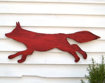 May include: A red wooden silhouette of a fox running, mounted on a white wooden wall.