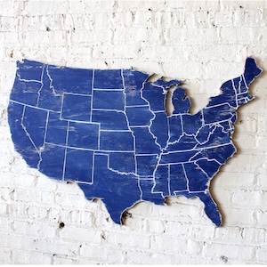 May include: A blue wooden map of the United States with white lines outlining each state.
