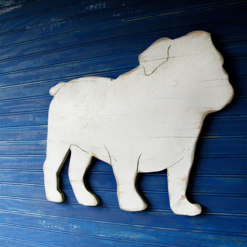 May include: White wooden cutout of a bulldog silhouette against a blue background.