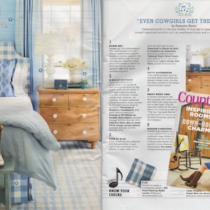 May include: A magazine spread featuring a bedroom with a blue and white gingham bedspread, a wooden dresser, and a pair of cowboy boots. The magazine cover features a rustic farmhouse with the text "Inspiring Rooms with Down-Home Charm" and "102 Fun Finds for Your Best Fried Chicken Ever! The New Guide to Rustic".