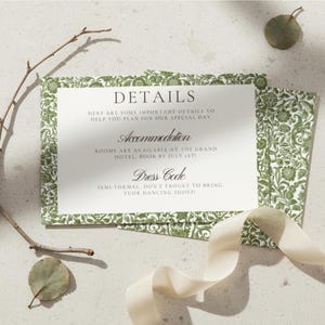 May include: A wedding details card with a green floral border and text that reads "DETAILS", "Accommodation", and "Dress Code". The card is accompanied by a ribbon, leaves, and a twig.