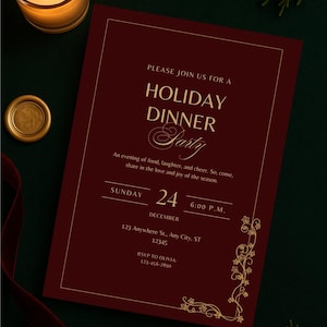 May include: A burgundy invitation for a holiday dinner party, featuring gold text and decorative elements. The invitation includes the date, time, and RSVP details. A lit candle and other decorations are in the background.