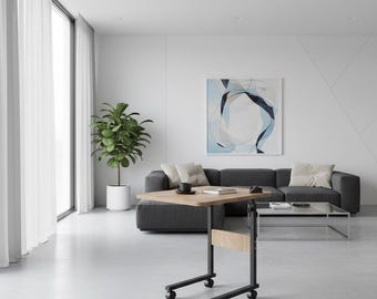 Puede incluir: Una mesa móvil regulable en altura con una tapa de madera clara y un marco de metal negro. La mesa está sobre ruedas y está colocada frente a un sofá gris. Una taza de café y un libro descansan sobre la mesa. La habitación tiene un diseño moderno.