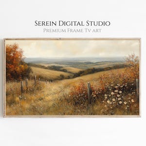 Op de afbeelding: Een landschapsschilderij in een houten lijst met glooiende heuvels, herfstbladeren en een draadafrastering met wilde bloemen op de voorgrond. De tekst SEREIN DIGITAL STUDIO PREMIUM FRAME TV ART staat boven het ingelijste kunstwerk.
