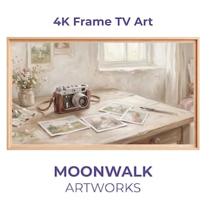 Pode incluir: Uma impressão de arte para TV 4K emoldurada com uma câmera vintage com estojo de couro marrom, várias fotografias e uma caneta em uma mesa de madeira. A obra de arte tem uma paleta de cores suaves e neutras. O texto "4K Frame TV Art" e "MOONWALK ARTWORKS" é visível.