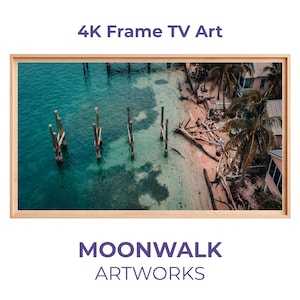 Puede incluir: Una impresión enmarcada de un paisaje costero con agua turquesa, una playa de arena y palmeras. La obra de arte está etiquetada como "4K Frame TV Art" y "MOONWALK ARTWORKS."