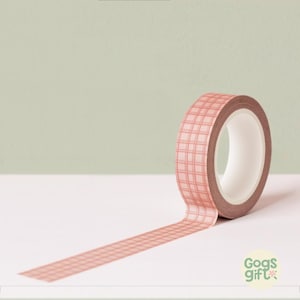 May include: A roll of decorative washi tape with a pink grid pattern. The tape is unrolled, revealing a portion of the grid design. The tape is on a white surface with a light green background. The brand name "Gogs Gift" is visible.