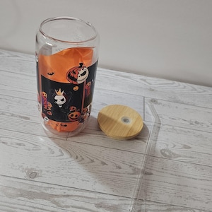 Puede incluir: Un vaso de vidrio transparente con un dise&ntilde;o tem&aacute;tico de Halloween, con calabazas y personajes espeluznantes. Incluye una tapa de bamb&uacute; y una pajita transparente. El vaso mide aproximadamente 13 cm de alto.