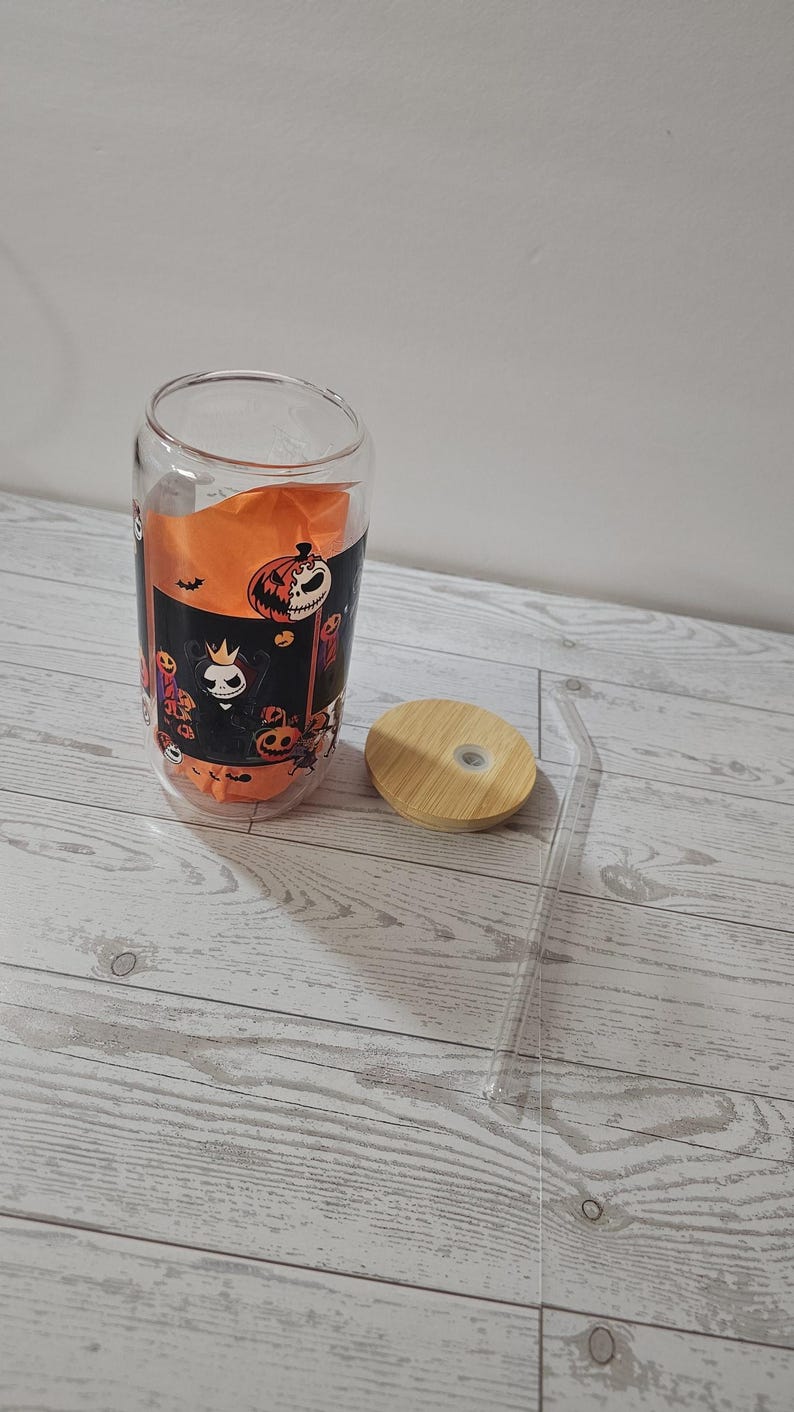 Puede incluir: Un vaso de vidrio transparente con un dise&ntilde;o tem&aacute;tico de Halloween, con calabazas y personajes espeluznantes. Incluye una tapa de bamb&uacute; y una pajita transparente. El vaso mide aproximadamente 13 cm de alto.