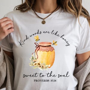 May include: White t-shirt featuring a honey jar illustration with bees and flowers. The text says "Kind words are like honey, sweet to the soul, Proverbs 16:24".